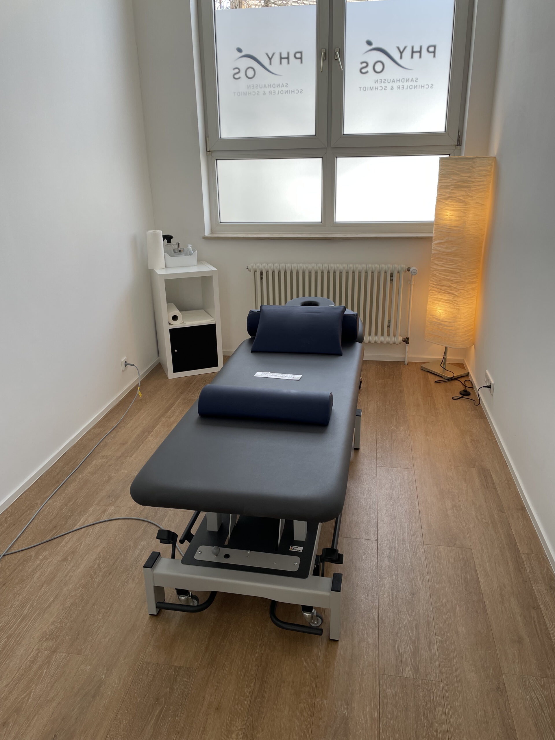 Behandlungsraum mit dunkelblauer Therapieliege und ruhiger Atmosphäre